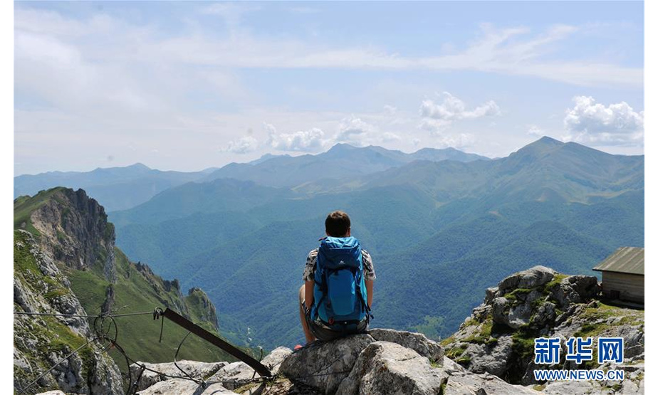 8月21日，一名登山者在山顶俯瞰欧洲之峰国家公园。 欧洲之峰位于西班牙北部，是西班牙认定的第一个国家公园。这里气候湿润，植被茂盛，层峦叠嶂，景色十分壮观。每年夏天，都有大量游客前来亲近大自然，享受山中的美景和清凉。 新华社记者 郭求达 摄