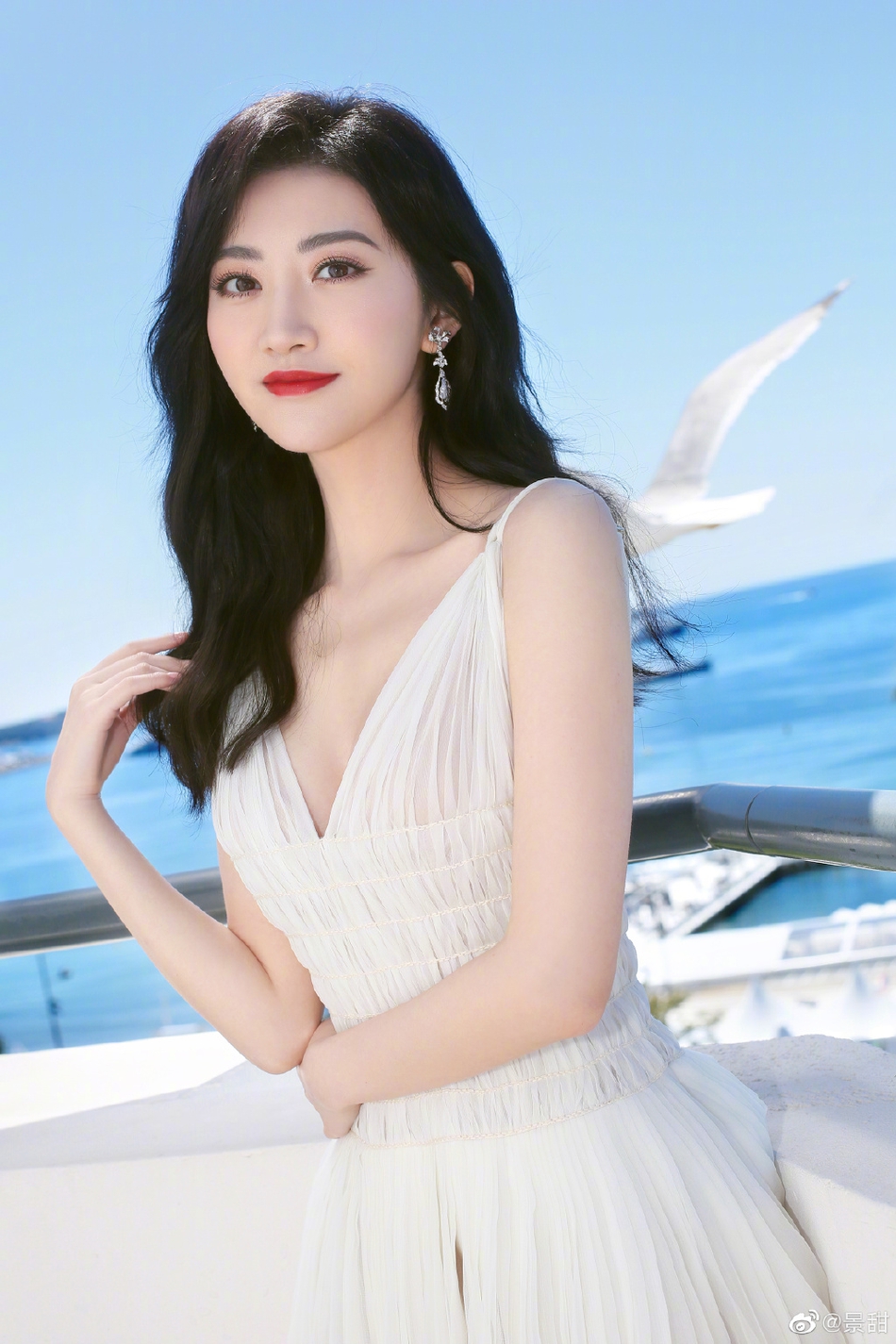 景甜在社交平台上晒出一组戛纳美照，只见她身穿纯白色吊带深V长裙，大秀性感身材。一头长卷发温柔披肩，妆容精致抹红唇气场十足。