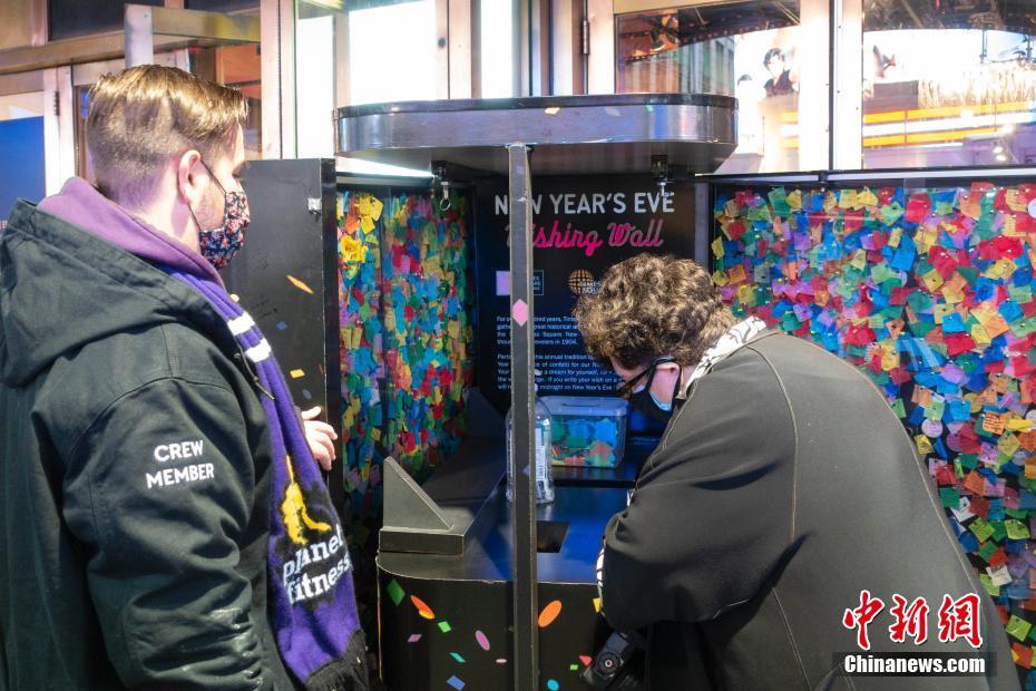 当地时间12月29日，美国纽约，民众在时报广场流动许愿墙前写下新年愿望。作为纽约市的迎新传统，时报广场许愿墙活动提供给民众在彩色纸屑上书写心愿的机会。在跨年夜活动上，当零点到来时，伴随彩色水晶球的降落，数千万张写满民众心愿的彩色纸屑将从时报广场高空撒下。 中新社记者 王帆 摄