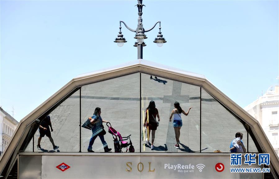 7月11日，在西班牙马德里，人们经过一座地铁站。 7月12日是今年“三伏”中“初伏”的第一天，这意味着高温高湿的“桑拿天”将逐渐成为天气“主角”，我国大部分地区开启“蒸煮模式”或“烧烤模式”。 而近日北半球多地也处在高温酷暑中。 新华社记者 郭求达 摄