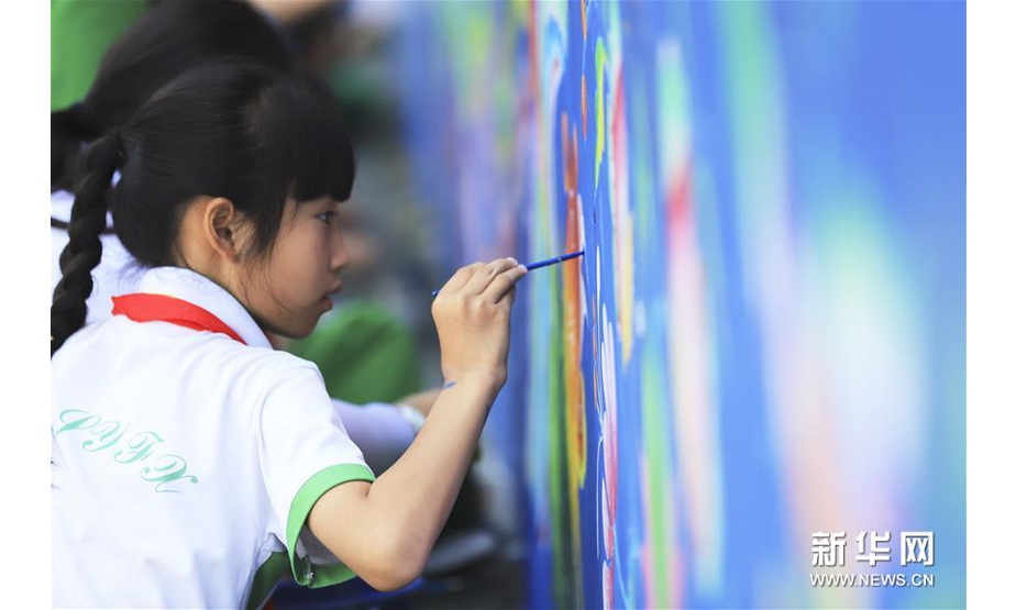 6月14日，在吉首大学师范学院附属小学吉首校区，学生在墙壁上画苗画。 新华社发（彭彪 摄）