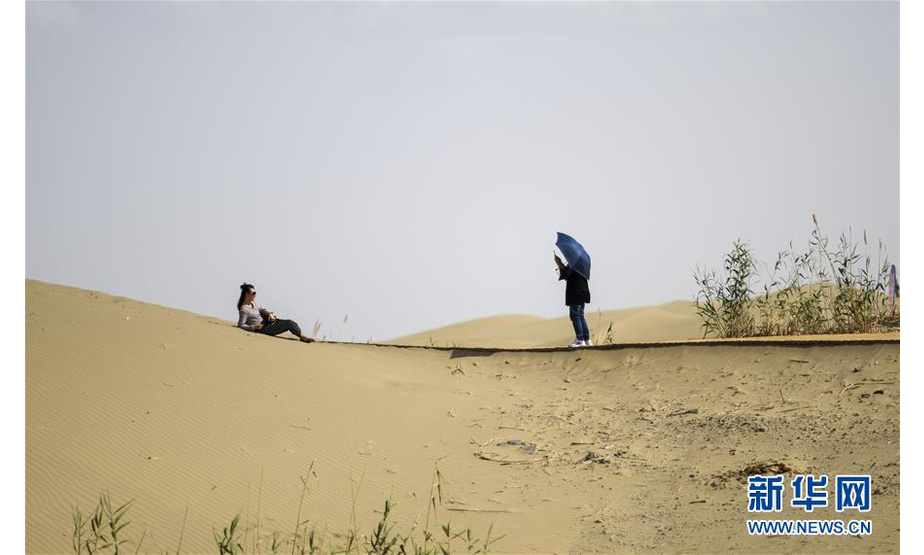 游客在罗布人村寨里拍照（6月19日摄）。 入夏以来，新疆尉犁县罗布人村寨景区迎来旅游旺季。根据景区提供的数据，自“五一”小长假至6月23日，罗布人村寨接待游客5.2万多人次，相比去年同期增长约78%。 新华社记者 赵戈 摄