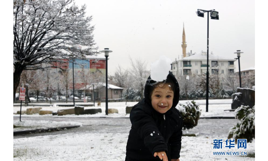 1月13日，在土耳其安卡拉，一名小女孩在路边玩雪。新华社发（穆斯塔法·卡亚摄）