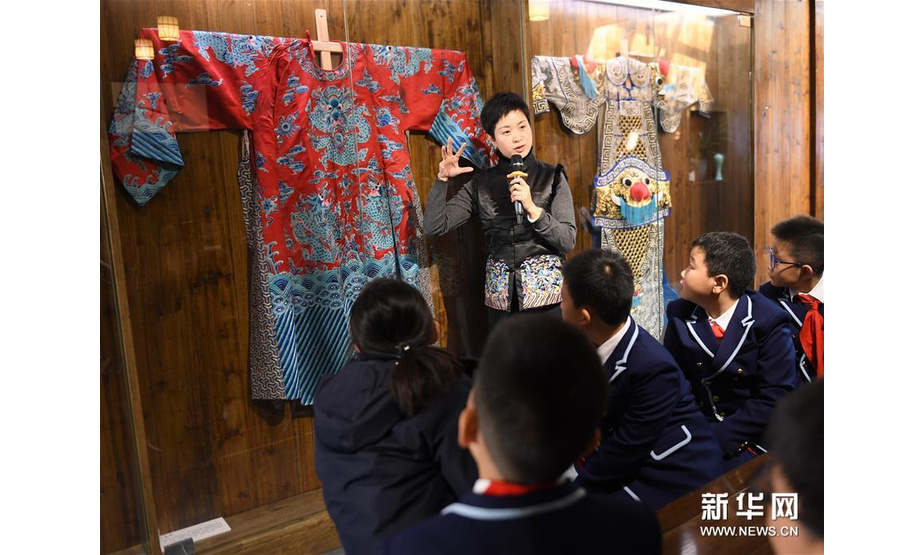 12月11日，杨崑（上）在“小河驿国际昆曲会客厅”为前来研学的小学生介绍昆曲戏服。新华社记者翁忻旸摄