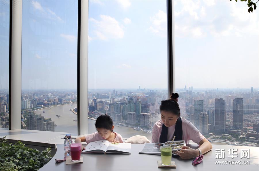 8月12日，顾客在朵云书院内阅读。 当日，位于上海中心大厦52层的朵云书院正式开业。在离地239米的空中、2000多平方米的空间内，朵云书院售卖16000多种、6万多册中外书籍。书店集阅读、艺术展览、品牌文创、社交休闲等多功能于一体，拥有独特的空中视野和“抬头看云、低头看书”的阅读环境。 新华社记者 刘颖 摄