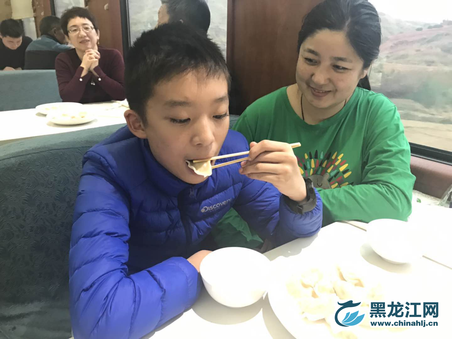 母亲看着儿子大口大口的吃着饺子，心想：这是又要长个儿了，真好！  宋菲 摄