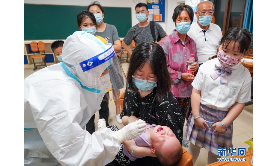 7月24日，医护人员在南京市江宁区龙西社区核酸检测点为小朋友进行核酸检测取样。新华社记者 李博 摄