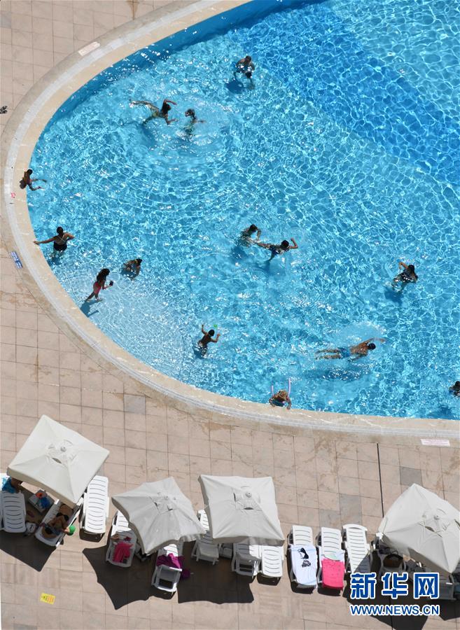 7月9日，人们在土耳其伊斯坦布尔一个室外游泳池消暑度夏。 7月12日是今年“三伏”中“初伏”的第一天，这意味着高温高湿的“桑拿天”将逐渐成为天气“主角”，我国大部分地区开启“蒸煮模式”或“烧烤模式”。 而近日北半球多地也处在高温酷暑中。 新华社记者 徐速绘 摄