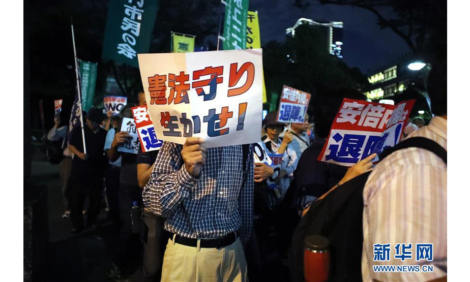 9月19日，在日本东京，一名民众手持标语参加游行。当日，近5000人在东京日比谷公园内参加反对新安保法集会。新华社记者 杜潇逸 摄