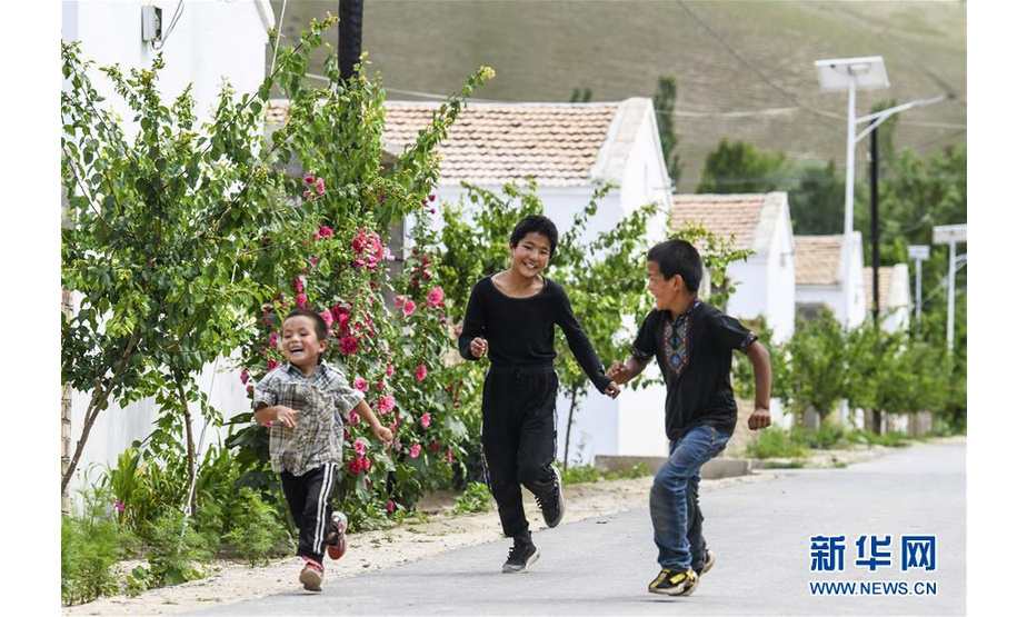 在新疆特克斯县境内的牧民定居点，小朋友在巷道内追逐玩耍（7月6日摄）。新华社记者 王菲 摄