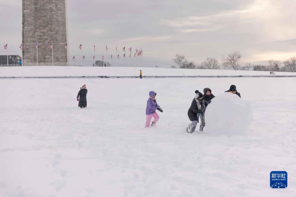 1月3日，在美国首都华盛顿，人们在华盛顿纪念碑附近堆雪人。当日，美国首都华盛顿及其周边地区普降暴雪。降雪导致部分航班晚点或取消，道路交通事故增多。新华社发（阿伦摄）
