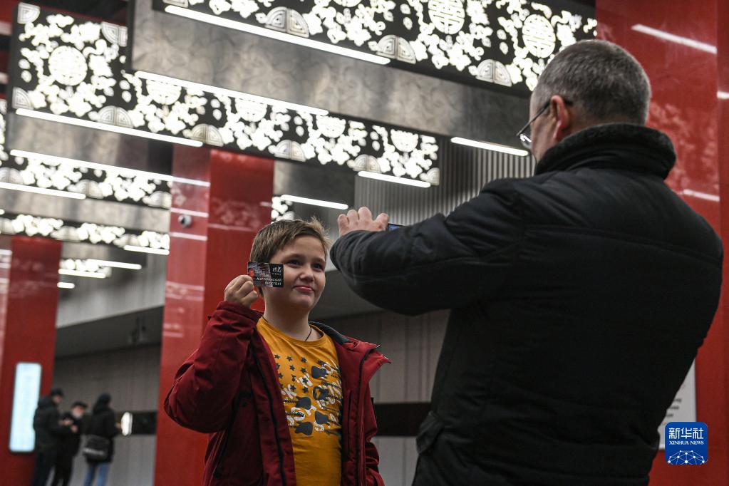 12月7日，在俄罗斯首都莫斯科，一名小朋友手持印有米丘林大街站照片的地铁票留影。

　　12月7日，由中国铁建承建的莫斯科地铁第三换乘环线西南段投入运行。俄罗斯总统普京以视频连线形式出席通车仪式并宣布正式开通。2017年1月，中国铁建中标莫斯科地铁第三换乘环线西南段项目，标段全长5.4公里，包含阿明耶沃站、米丘林大街站、韦尔纳茨基大街站3个车站和9条盾构隧道建设任务，这也是俄罗斯首次在地铁施工领域引进中国企业。走进米丘林大街地铁站，红色立柱、团寿纹、祥云等中国元素随处可见。这里已经成为中俄友谊的新地标，展现出“一带一路”上的跨文化盛景。

　　新华社发（叶甫盖尼·西尼岑摄）