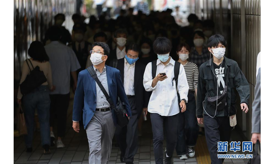 5月25日，在日本东京，行人戴着口罩经过新宿街头。 日本首相安倍晋三25日晚宣布，日本全国解除紧急状态。此前日本47个都道府县中已仅剩东京都、北海道等5个维持紧急状态。 新华社记者 杜潇逸 摄