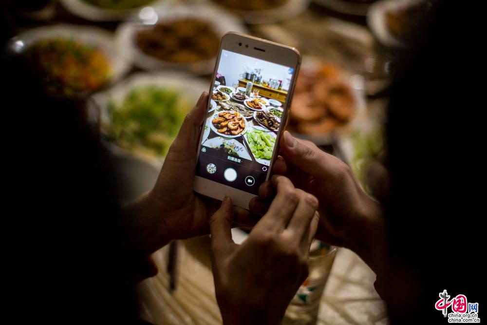 妈妈换了新的手机，也学会了拍照在朋友圈里“秀”，今天自己和妈妈一起把这一桌子饭菜拍下来。其实春节的这一顿团圆饭吃什么真的不重要，重要的是能和妈妈、和家里亲人在一起。也许再过几年妈妈的手会有更多的皱纹，也许不会在那个小小的厨房继续忙碌，而我们也不再会让她觉得炒菜时那么“笨拙”。因为无论什么时候，妈妈的手都会一直拉着我们的手……中国网记者 郑亮 摄