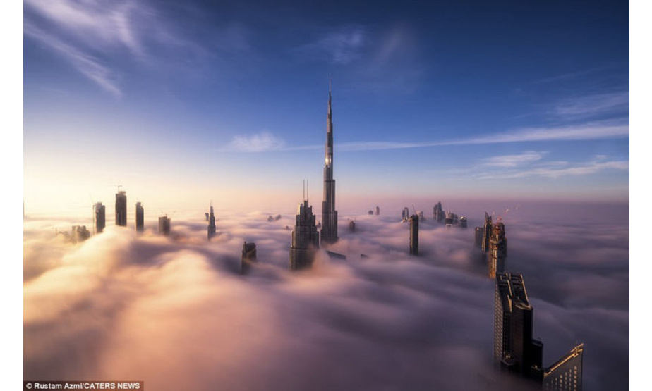 迪拜摩天大楼突破浓雾与云层，宛如童话中的仙境。日出之时，金色的太阳光线洒落下来将整个云层变成了一片沙滩，而整座城市就好像是被沙浪席卷了一般。（编译 张琳 审稿 徐祥丽）