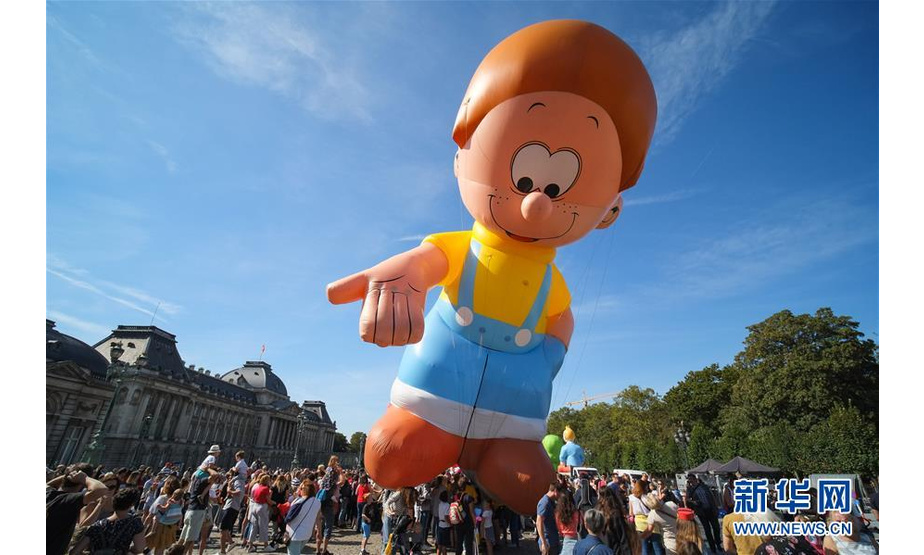 9月15日，人们在比利时首都布鲁塞尔观看卡通气球大巡游。 当日，布鲁塞尔举行第十届布鲁塞尔漫画节卡通气球大巡游，形态各异的卡通气球从街头巷尾穿行而过，吸引大批市民和游客。 新华社记者 张铖 摄
