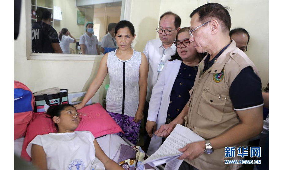 7月16日，在菲律宾首都马尼拉的一家医院，菲律宾卫生部部长弗朗西斯科·杜凯（右一）在登革热病房看望病人。 菲律宾卫生部15日公布的数据显示，今年以来菲律宾登革热病例激增。据当地媒体报道，今年该国至少有450人因感染登革热死亡。 新华社发（鲁埃勒·乌马利摄）