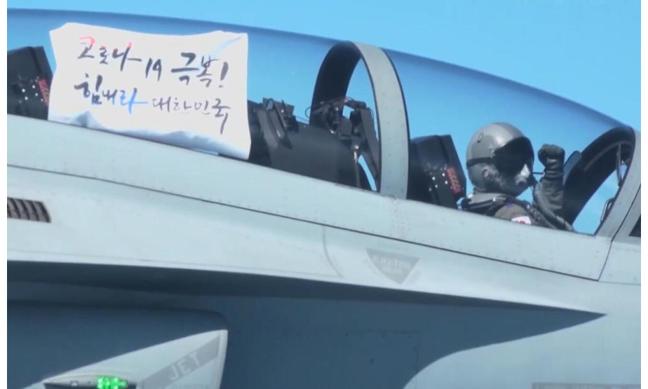 飞行员在座舱里展示“战胜新冠病毒！加油吧，大韩民国！”的标语