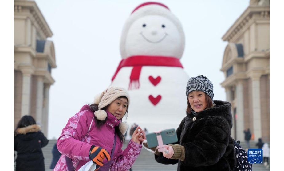 1月9日，游客在哈尔滨松花江畔的巨型雪人前留影。

　　近日，一个巨型雪人亮相冰城哈尔滨松花江畔，吸引市民游客前来打卡拍照。戴着红帽子、红围脖，嘴角上扬的巨型雪人高约18米，宽约13米，用雪量2000余立方米。

　　新华社记者 王建威 摄