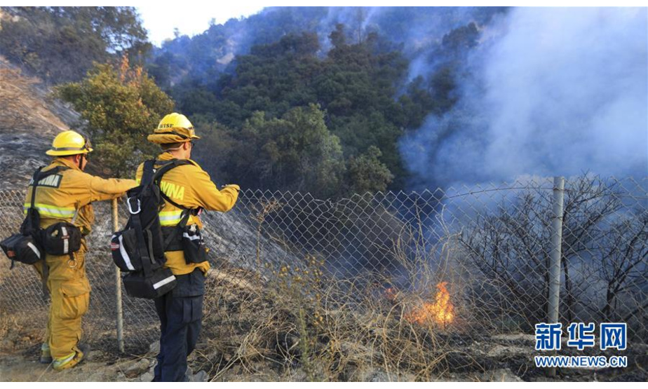 10月12日，在美国加利福尼亚州西尔马，消防员观察一处山火。新华社记者 李颖 摄