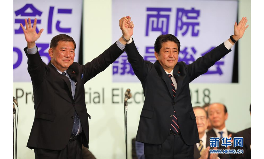 9月20日，在日本东京自民党总裁选举现场，成功连任自民党总裁的日本首相安倍晋三（右）与石破茂一同举起双手。 新华社记者 杜潇逸 摄