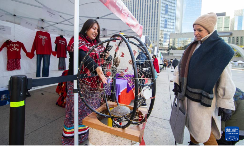 11月4日，一名女子在加拿大多伦多市政广场观看一件原住民艺术品。当日，一场为期两天的原住民文化展示活动在多伦多开幕。新华社发（邹峥摄）