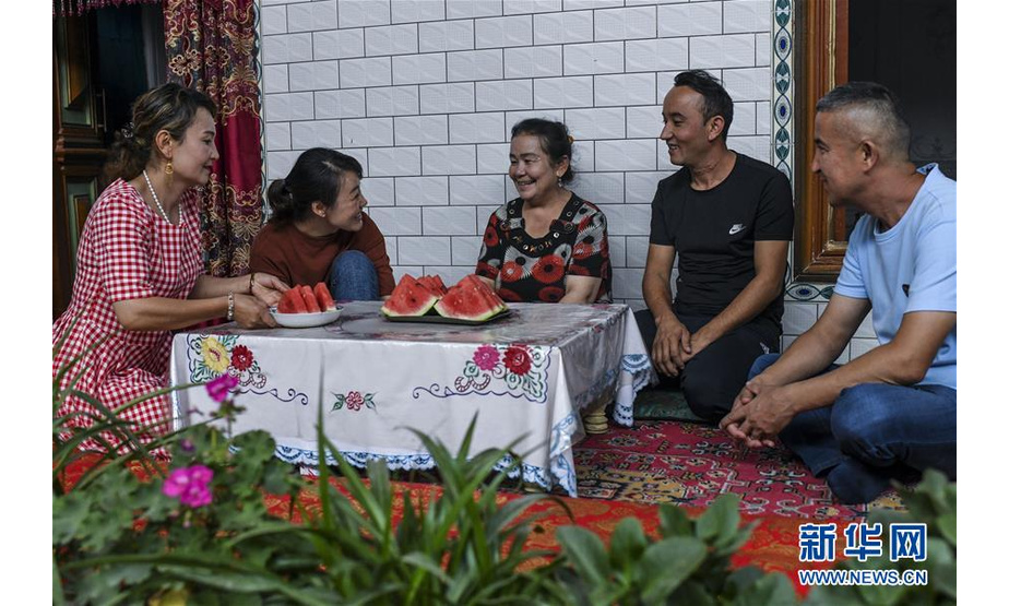 在新疆喀什市乃则尔巴格镇前进村，新疆维吾尔自治区妇联驻喀什市乃则尔巴格镇前进村“访惠聚”工作队工作人员相虹（左二）和热甫卡提·买买提（右一）在村民色里满·苏里坦（中）家中了解花卉种植情况（8月18日摄）。新华社记者 王菲 摄