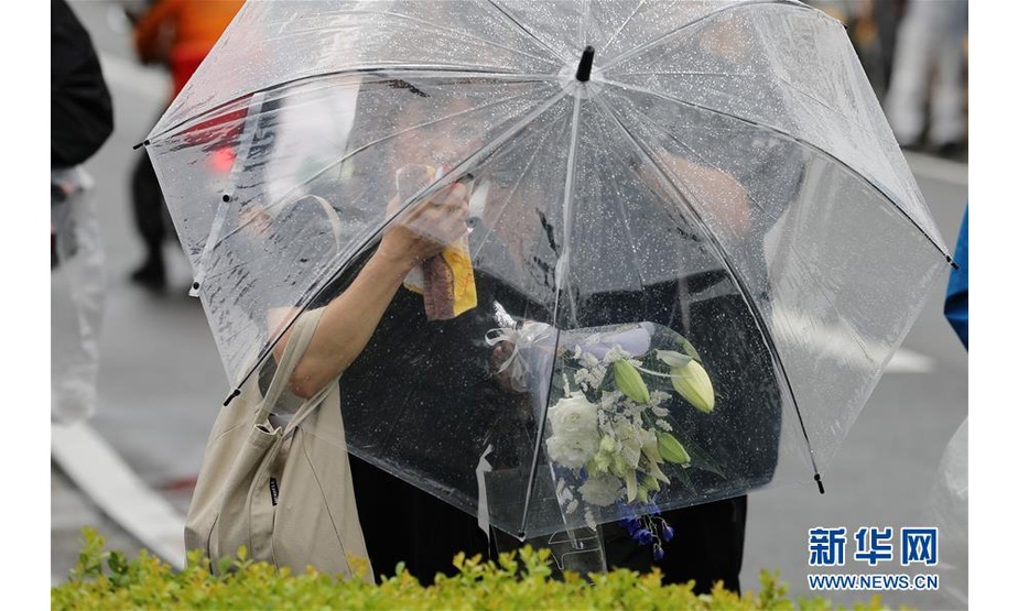 7月19日，在日本京都纵火杀人案现场附近，一名市民撑伞前来献花。 日本京都府警搜查本部19日宣布，已将京都动漫工作室大火定性为纵火杀人案。建筑物内部构造、火势蔓延速度快等因素造成重大伤亡。 据警方通报，这起纵火杀人案的嫌疑犯是一位名叫青叶真司的41岁男子。该男子于当地时间18日上午10点35分左右纵火，当时工作室内共有74人在工作。大火造成33人死亡、36人受伤（含嫌犯在内），仅有6人成功脱险。 新华社记者杜潇逸摄