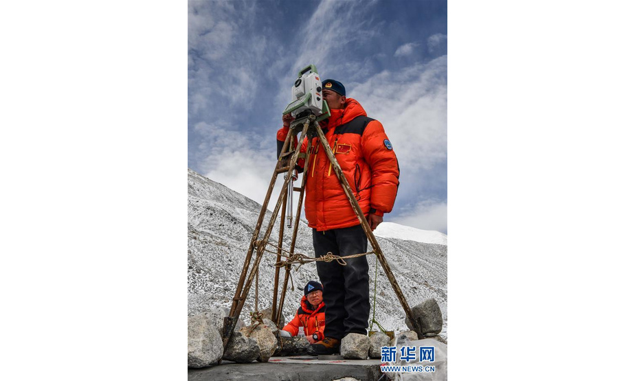 自然资源部第一大地测量队队员郑林（站立者）和武光伟在对珠峰峰顶进行交会观测（5月27日摄）。 当日，2020珠峰高程测量登山队成功登顶后，在珠峰大本营的珠峰高程起算点，自然资源部第一大地测量队队员利用全站仪等仪器对珠穆朗玛峰峰顶进行交会观测。 新华社记者 普布扎西 摄