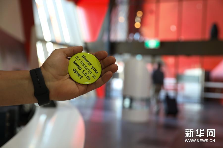 6月2日，在澳大利亚堪培拉，澳国家博物馆的工作人员手持提醒人们保持1.5米社交距离的标识。新华社发（储晨摄）