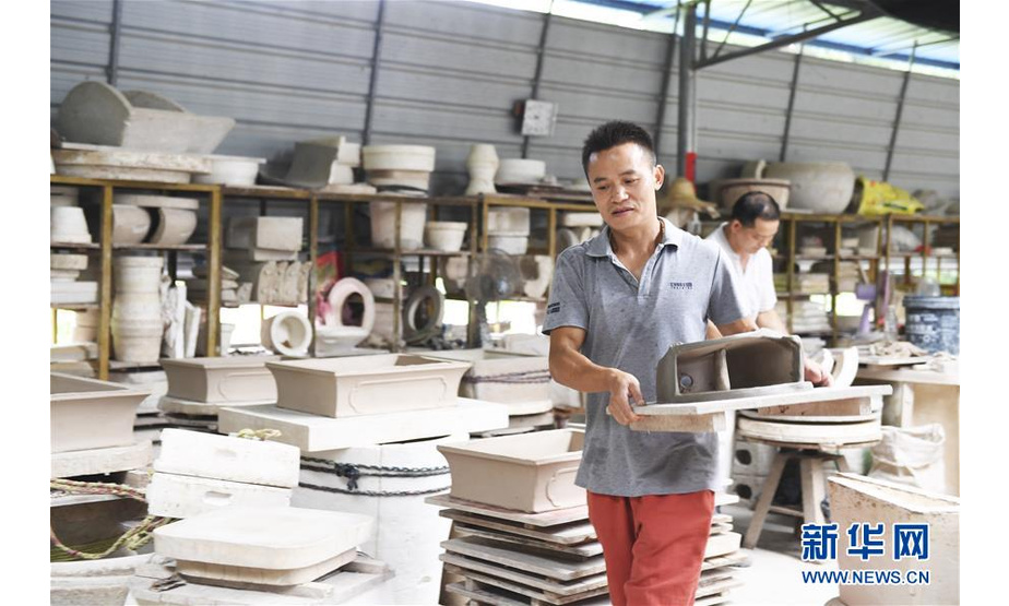 赵勇在自己创办的陶瓷制品加工厂内搬运制作成型的壁挂式花瓶坯体（8月11日摄）。  新华社记者 曹祎铭 摄