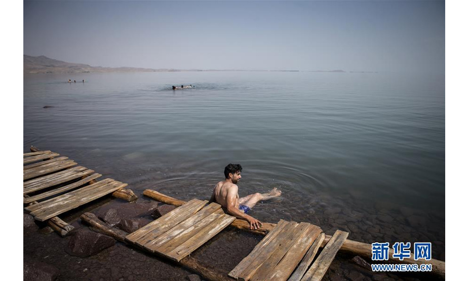 6月17日，一名游客坐在伊朗乌鲁米耶湖边。 近日，位于伊朗西北部的乌鲁米耶湖水位上升，吸引了众多游客前来游玩。 新华社发（艾哈迈德·哈拉比萨斯摄）