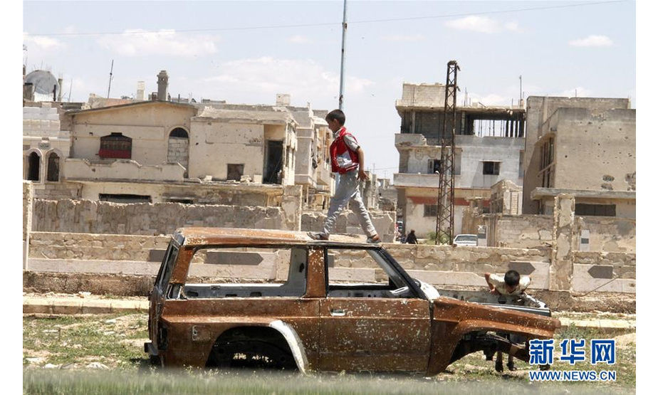 5月16日，在叙利亚霍姆斯省泰勒比塞，男孩在废弃的汽车上玩耍。叙利亚霍姆斯省省长塔拉勒·巴拉齐16日告诉新华社记者，随着最后一批反政府武装人员当天从霍姆斯省北部撤离，叙政府已全面收复中部省份霍姆斯。新华社发（胡马姆·谢赫·阿里 摄）