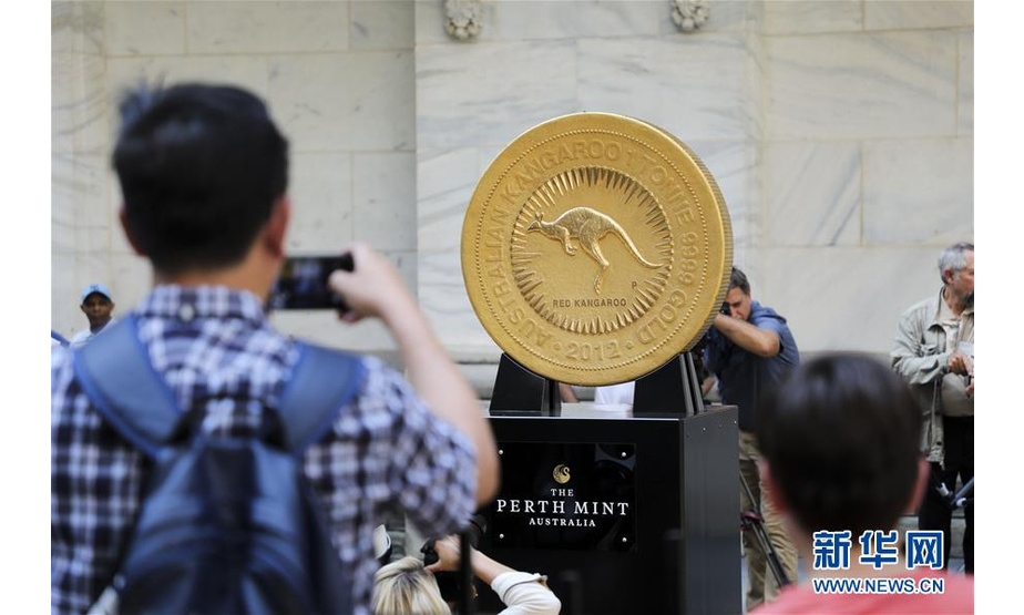 7月16日，人们在美国纽约证券交易所前观看超大金币。 当天，一枚重达一吨的金币在纽约展出，以庆祝一家澳大利亚黄金交易所的基金在纽约证券交易所上市。这枚金币由99.99%纯金铸造，直径约80厘米，厚度超过12厘米。 新华社记者 王迎 摄