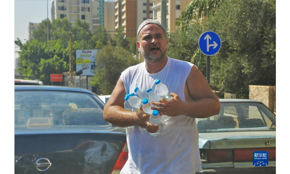 9月21日，在黎巴嫩贝鲁特一加油站前，一名男子在等待加油的车辆间售卖瓶装水。

　　9月22日，黎巴嫩能源部在不到一周的时间内第二次提高汽油价格，95号和98号汽油的价格上涨了15%左右。新华社记者 刘宗亚 摄