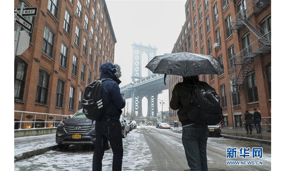 2月20日，在美国纽约曼哈顿大桥附近一商业区，两名男子在雪中观赏风景。

　　当日，纽约迎来降雪天气。

　　新华社记者 王迎 摄