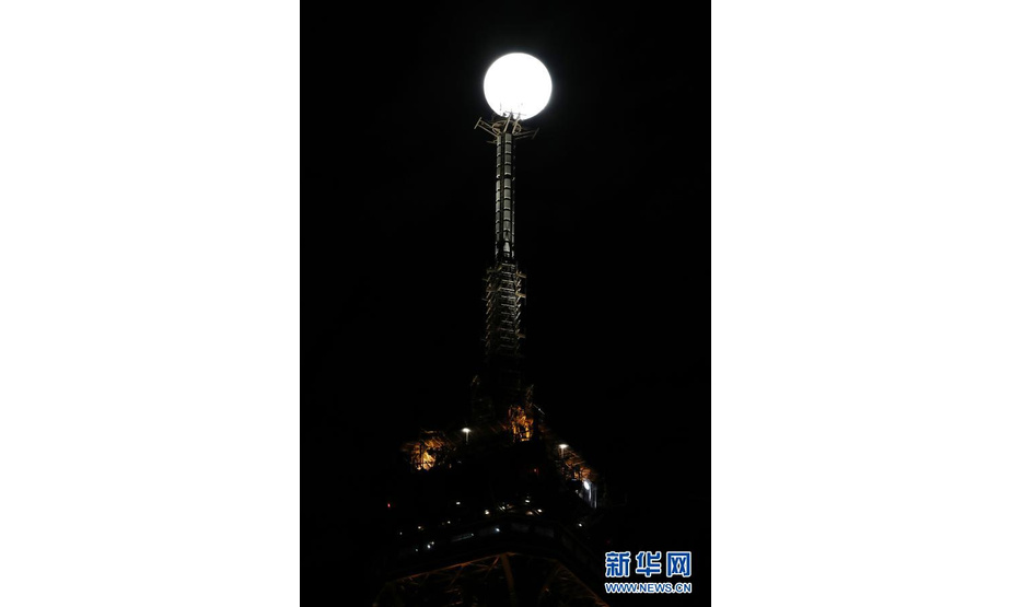 2月26日，一轮明月在法国巴黎埃菲尔铁塔附近升起。

　　新华社记者 高静 摄